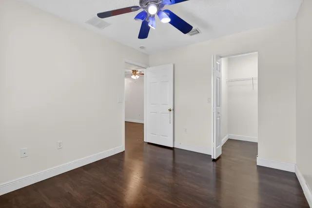 a view of an empty room with a ceiling fan and window