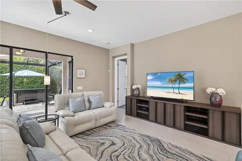 a living room with furniture a flat screen tv and a floor to ceiling window
