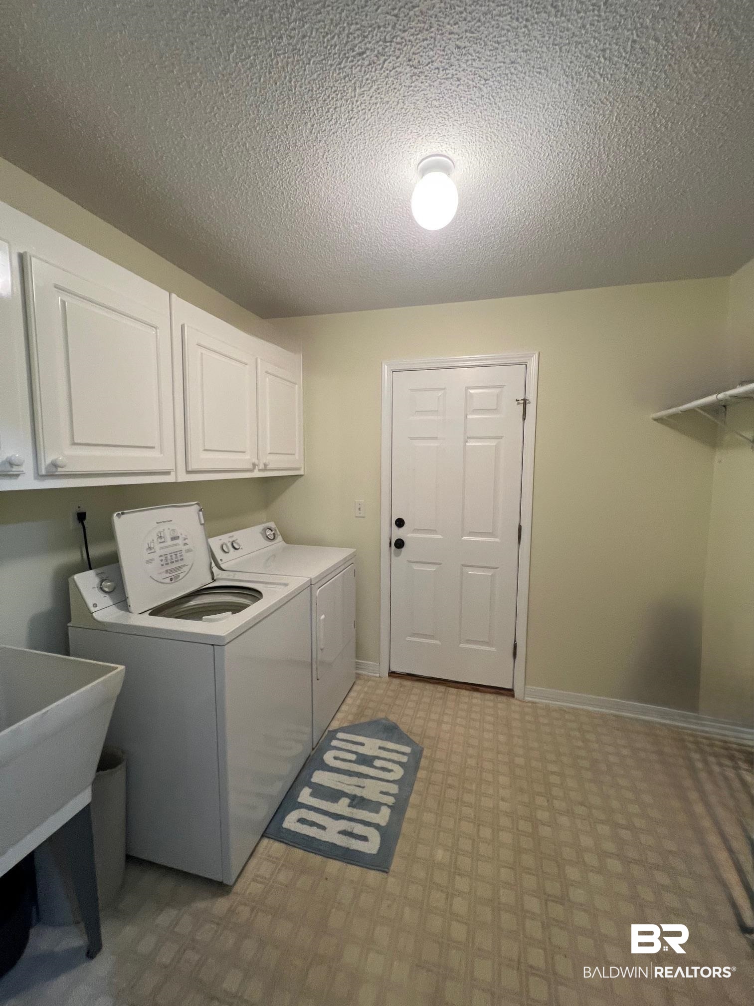 2204 Club House Drive Lillian, AL 36549 - Photo 18 of 38 Laundry room with independent washer and dryer, cabinet space, light floors, and a textured ceiling