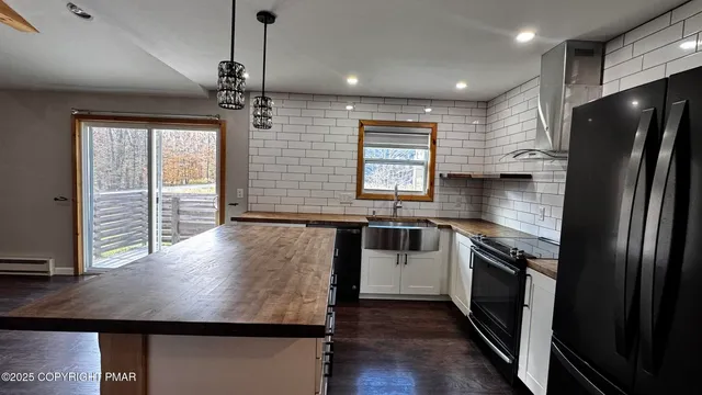 a kitchen with kitchen island a counter space a sink appliances and a window