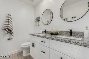 a bathroom with a granite countertop toilet sink and mirror