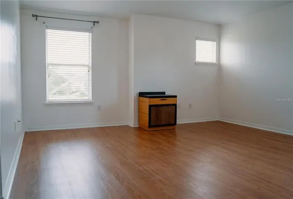 an empty room with wooden floor and windows