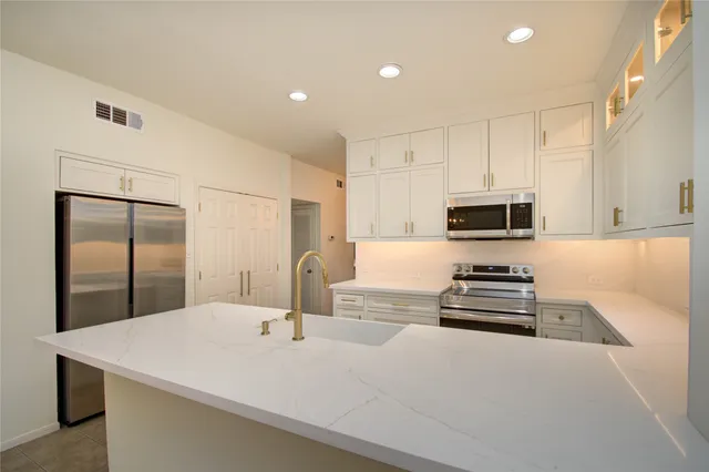 a kitchen with stainless steel appliances a stove a sink a refrigerator and cabinets