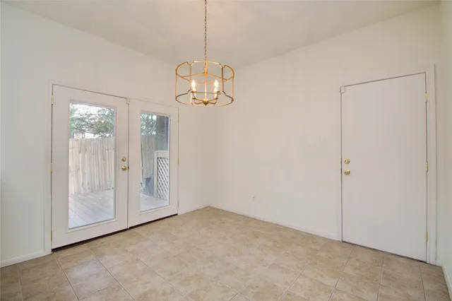 a view of empty room with wooden floor and chandelier