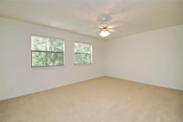 an empty room with windows and fan