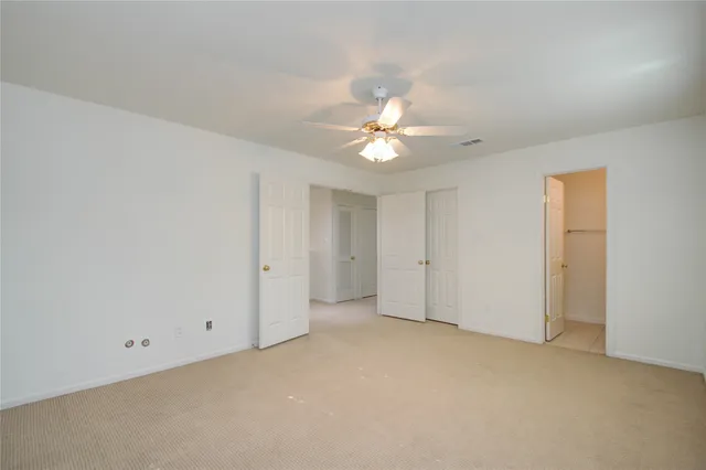 an empty room with a ceiling fan and a window
