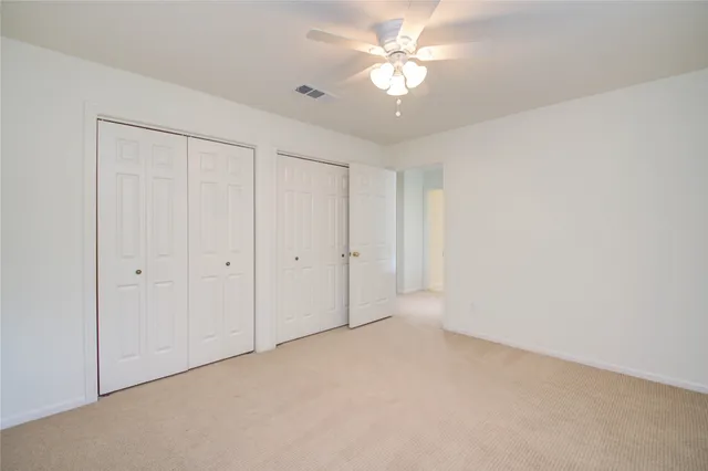 an empty room with a ceiling fan and a window