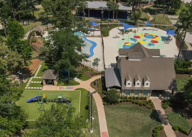 an aerial view of a house with swimming pool and large trees