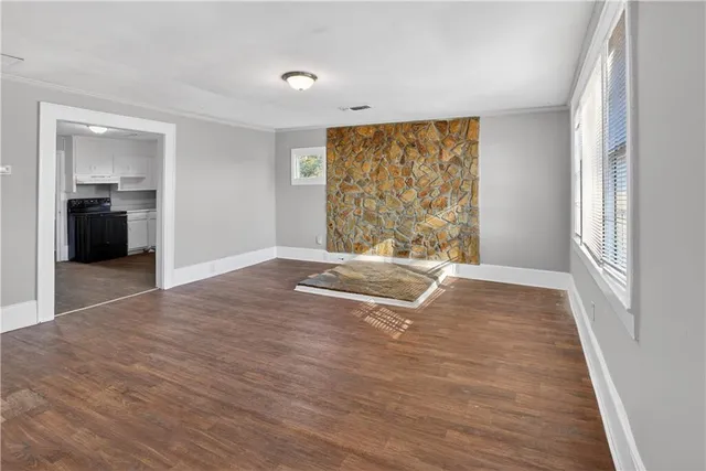a view of an empty room with wooden floor and closet