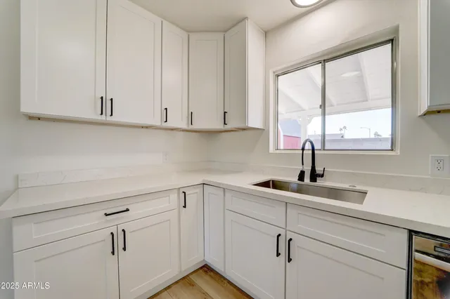 a kitchen with white cabinets and window