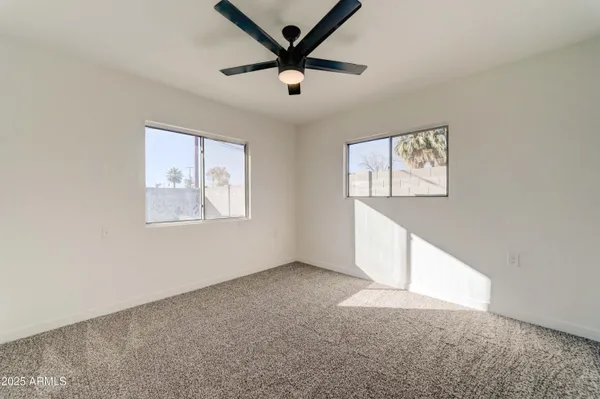 an empty room with windows and fan