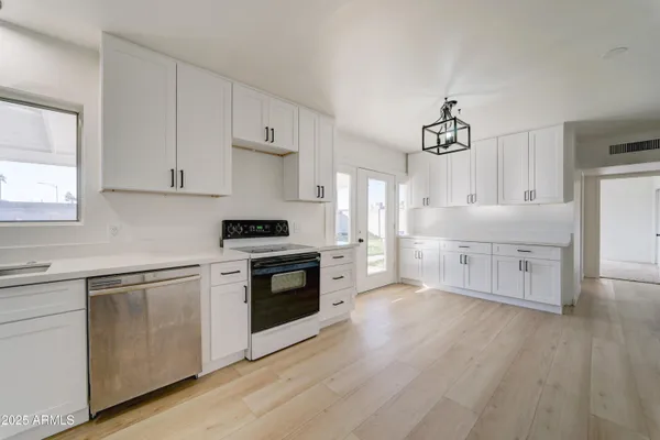 a kitchen with stainless steel appliances white cabinets and wooden floors