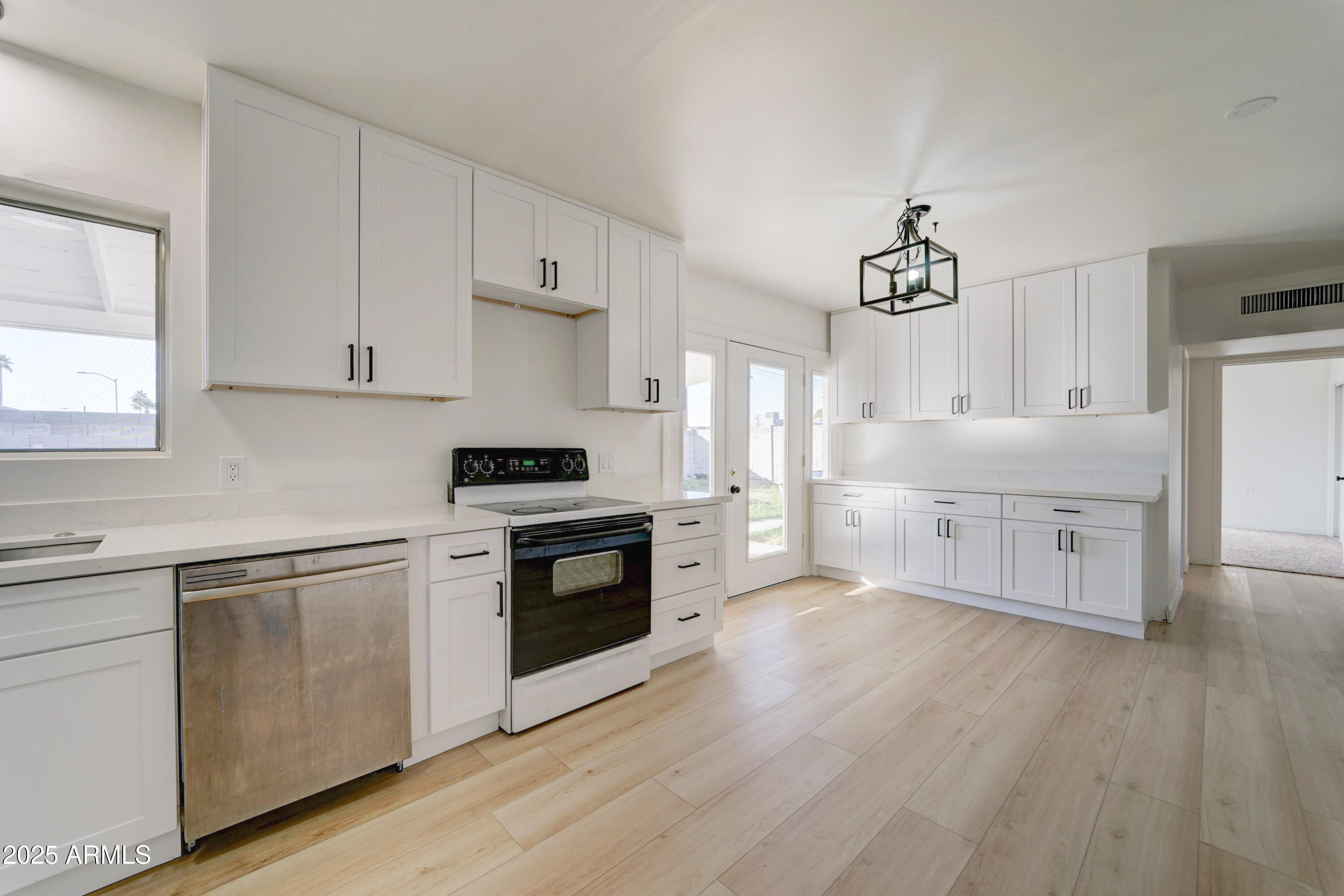 2039 West Northview Avenue Phoenix, AZ 85021 - Photo 10 of 30 a kitchen with stainless steel appliances white cabinets and wooden floors