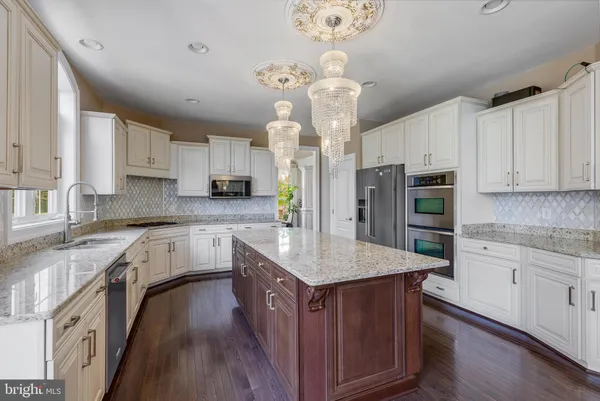 a kitchen with stainless steel appliances granite countertop a sink a stove top oven a counter space and cabinets