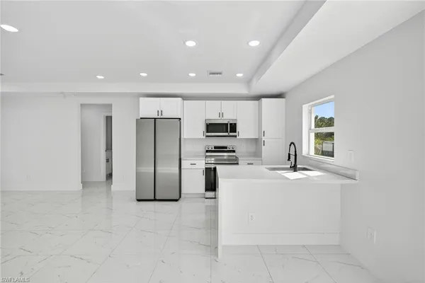 a large kitchen with stainless steel appliances granite countertop a stove a sink and a refrigerator