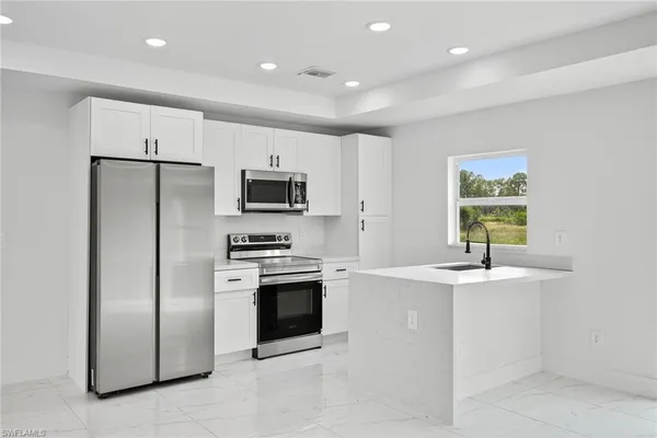 a kitchen with stainless steel appliances granite countertop a sink a stove a refrigerator a window