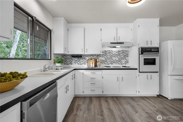 a kitchen with granite countertop white cabinets white appliances and sink