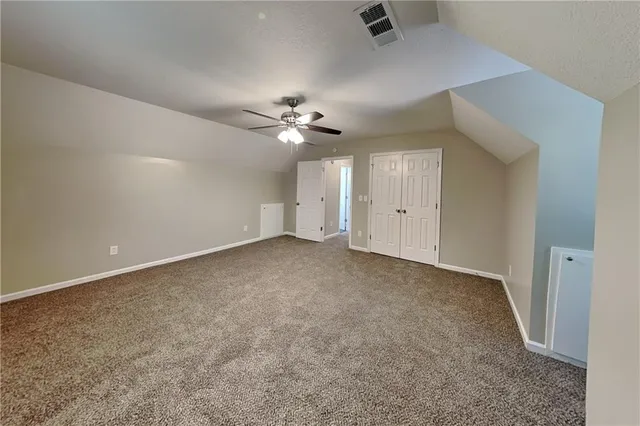 an empty room with chandelier fan and windows