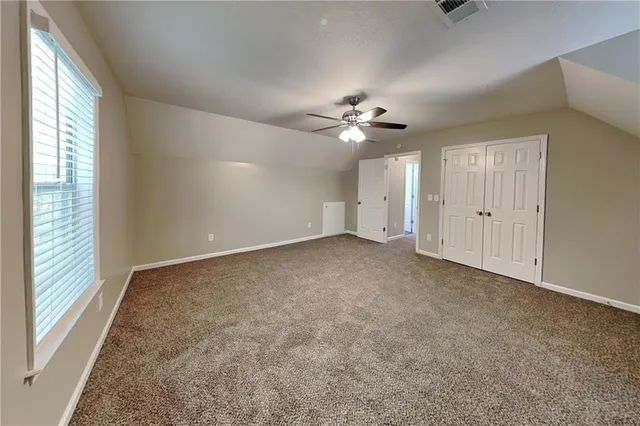 an empty room with windows and chandelier fan