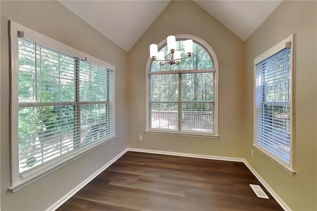 a view of an empty room with wooden floor and a large window