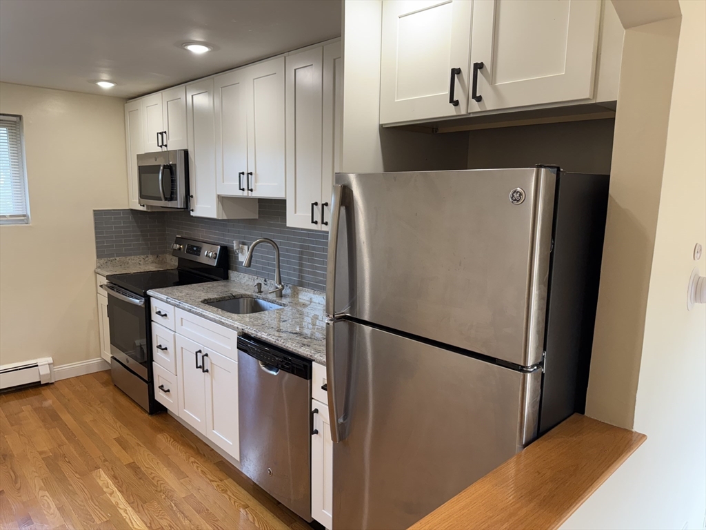 40 Westgate Road, Unit 5 Chestnut Hill, MA 02467 - Photo 3 of 33 a kitchen with stainless steel appliances granite countertop a refrigerator a stove a sink and a microwave