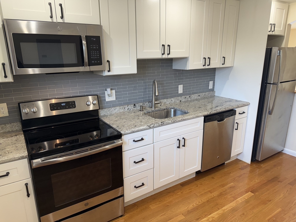 40 Westgate Road, Unit 5 Chestnut Hill, MA 02467 - Photo 6 of 33 a kitchen with granite countertop cabinets stainless steel appliances and wooden floor