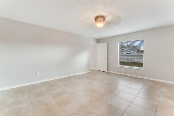an empty room with windows and chandelier fan