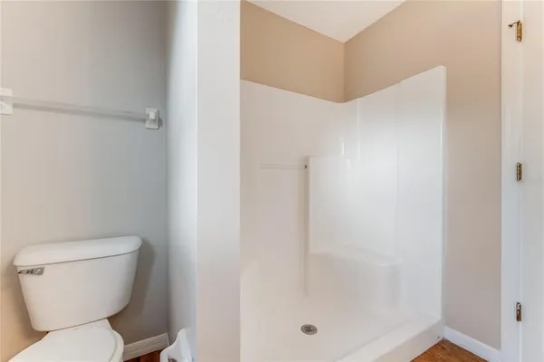 a white toilet sitting next to a shower