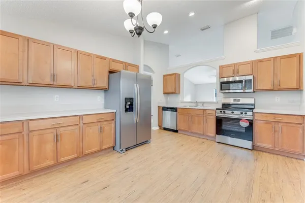 a kitchen with stainless steel appliances granite countertop a refrigerator a sink dishwasher a stove and white cabinets with wooden floor