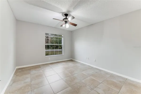 a view of an empty room with windows and chandelier fan