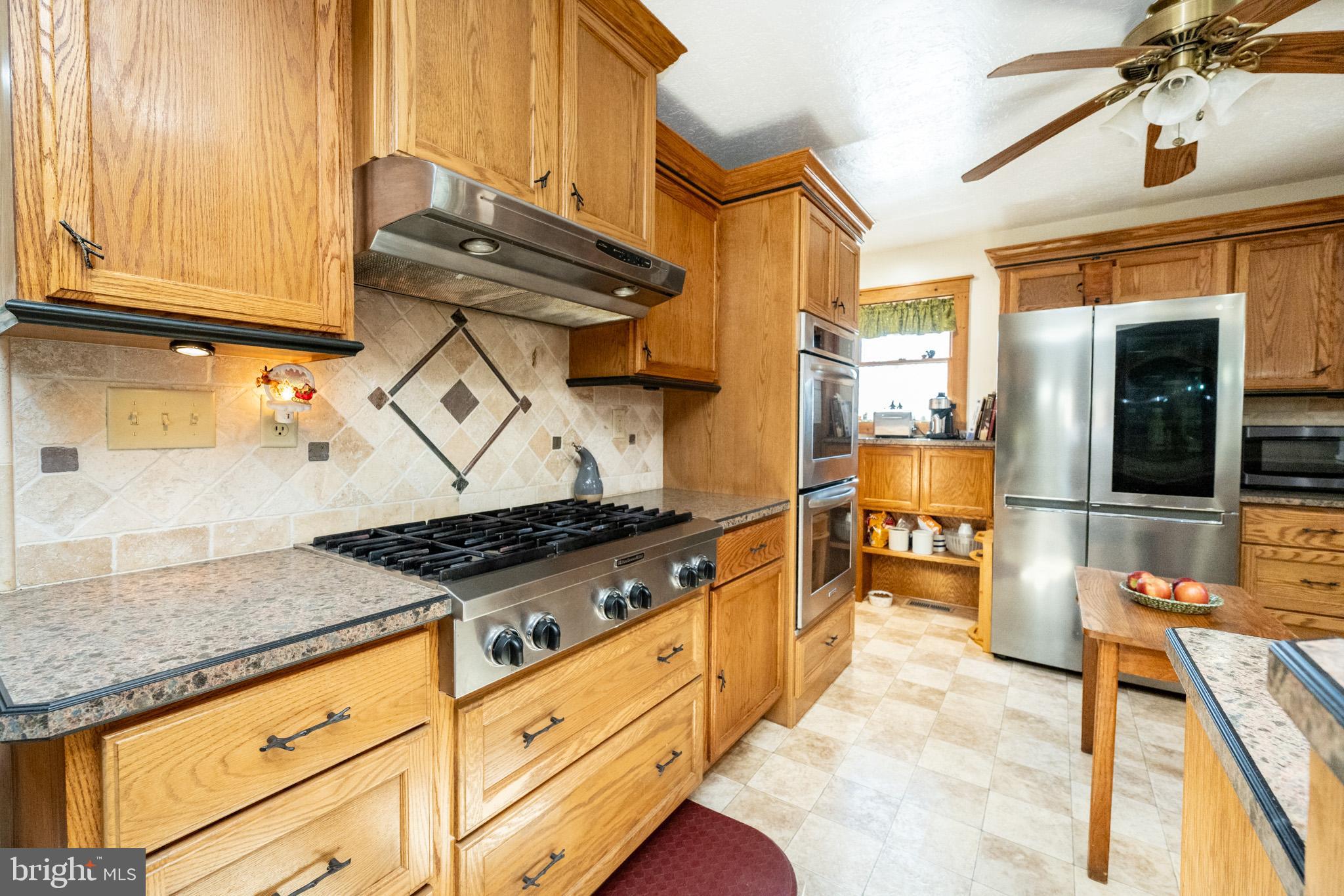328 Stool Rock Road Oakland, MD 21550 - Photo 38 of 133 a kitchen with granite countertop a sink a stove and a wooden cabinets