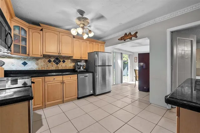 a kitchen with granite countertop a refrigerator stove top oven and sink