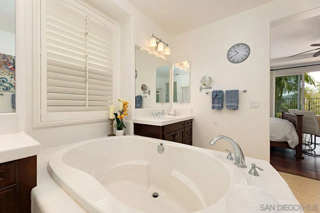 16076 Cayenne Ridge Road San Diego, CA 92127 - Photo 22 of 43 a bathroom with a tub a double vanity sink a mirror a window and a shower