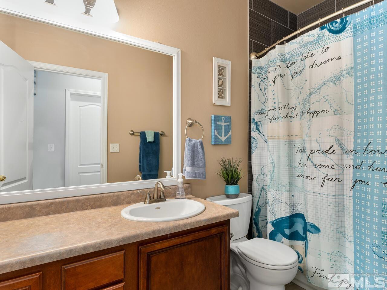 10805 Dancing Aspen Drive Reno, NV 89521 - Photo 20 of 25 a bathroom with a granite countertop sink a toilet a mirror and shower