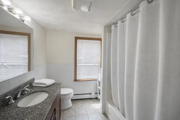 a bathroom with a granite countertop sink toilet a mirror and a tub
