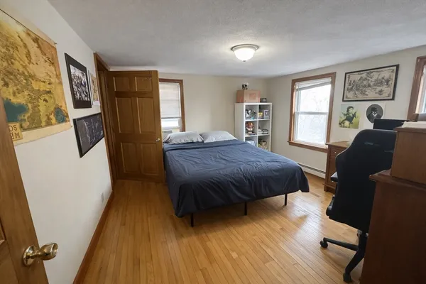 a spacious bedroom with a bed and wooden floor
