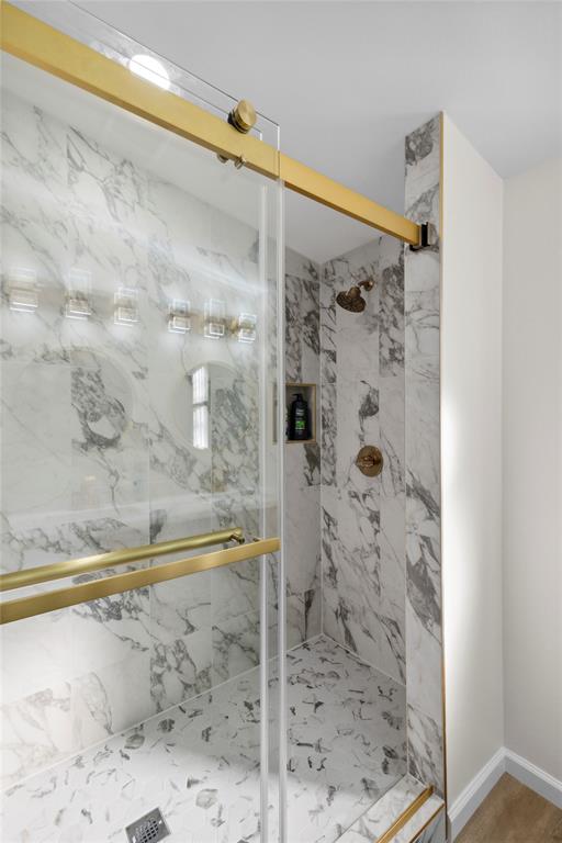 141 Mallard Road Ringgold, LA 71068 - Photo 5 of 33 Luxurious shower enclosure featuring a frameless glass door with brass hardware, marble-look tiled walls, a tiled shower pan, a built-in shower niche, and a brass shower head and controls