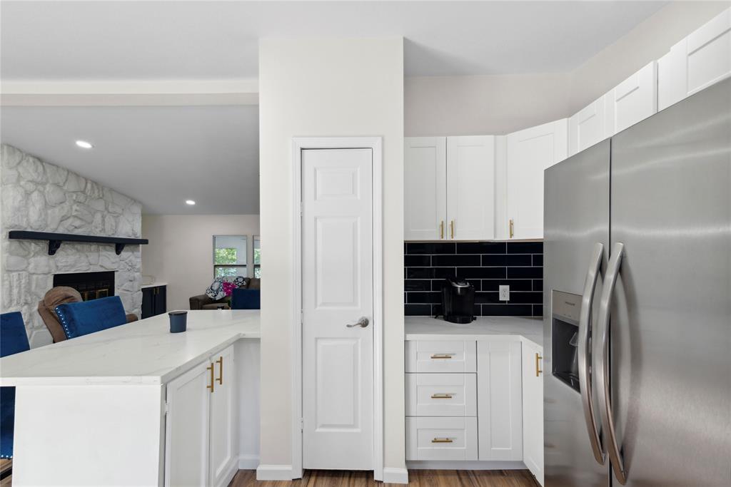 141 Mallard Road Ringgold, LA 71068 - Photo 9 of 33 White kitchen cabinetry featuring gold-tone hardware, a dark subway tile backsplash, and a stainless steel refrigerator