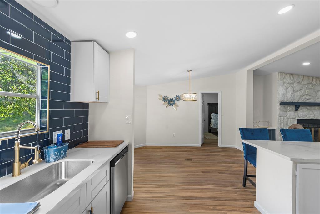 141 Mallard Road Ringgold, LA 71068 - Photo 10 of 33 Modern kitchen featuring a stainless steel sink, gold-finish faucet, white cabinetry, and dark blue subway tile backsplash