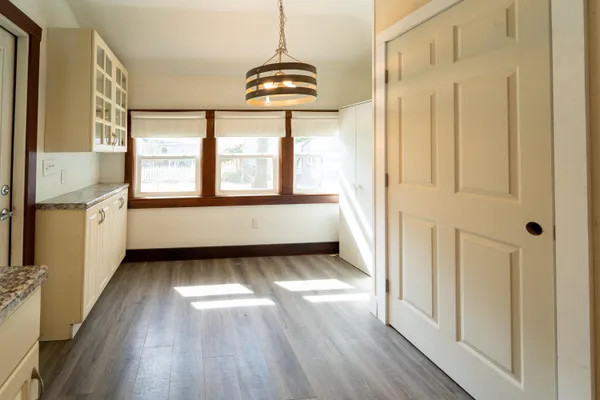 a view of an empty room with a window and wooden floor