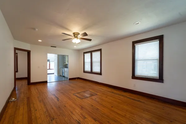 a view of an empty room with wooden floor and a window