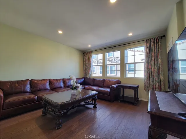 a living room with furniture a flat screen tv and wooden floor