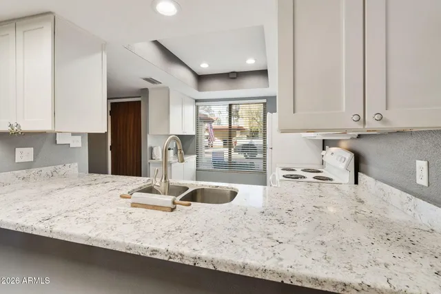 a kitchen with granite countertop a sink a stove and a wooden floors