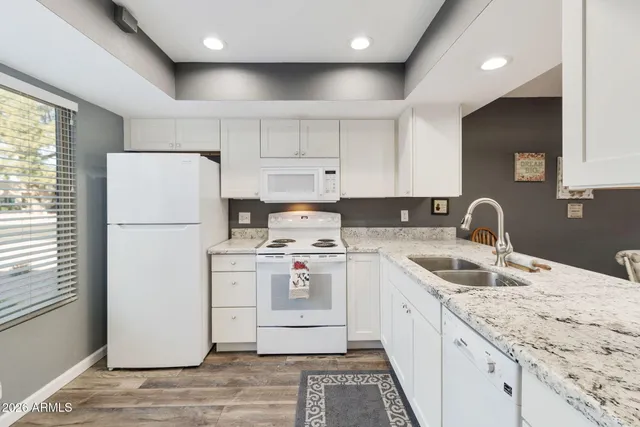 a kitchen with a sink a refrigerator and white cabinets