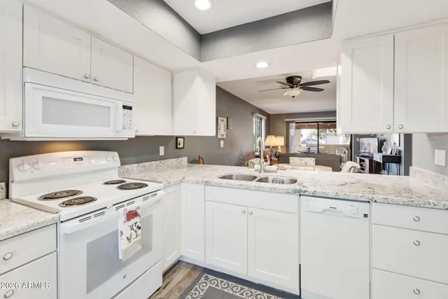 a kitchen with granite countertop white cabinets and white appliances