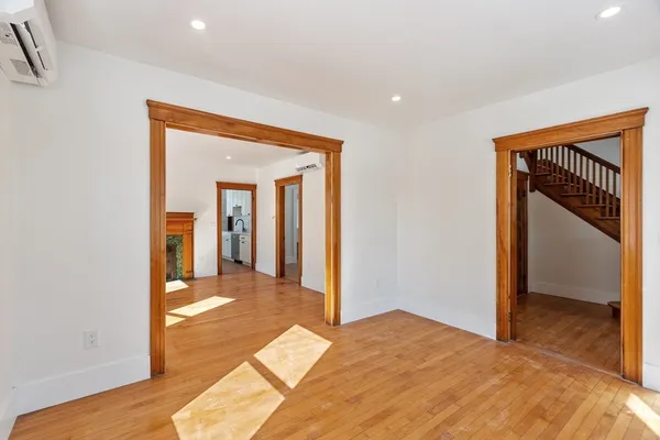 a view of a hallway to a room with wooden floor and staircase