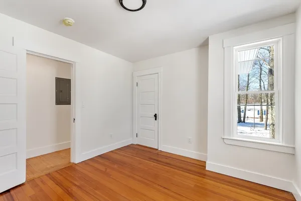a view of an empty room with wooden floor and a window