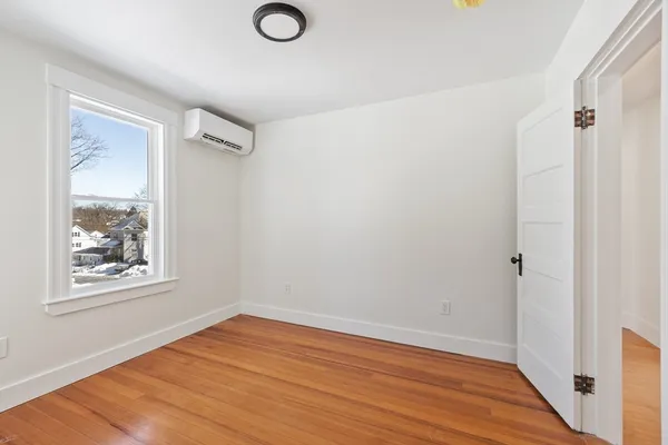 a view of an empty room with wooden floor and a window
