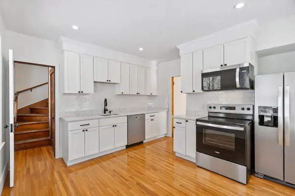 a kitchen with granite countertop white cabinets and stainless steel appliances