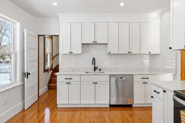 a kitchen with white cabinets and sink